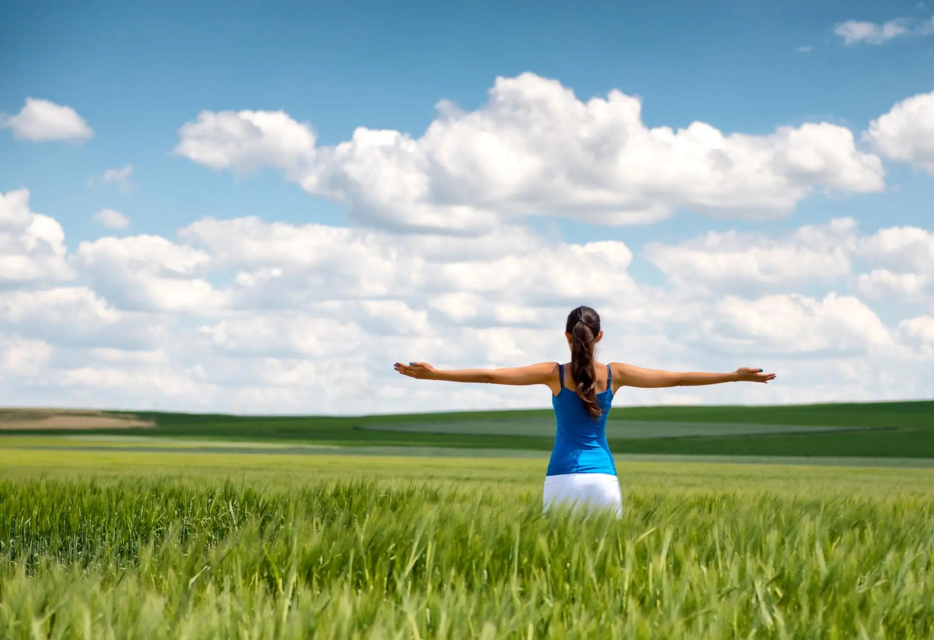 Woman in field with arms open happy